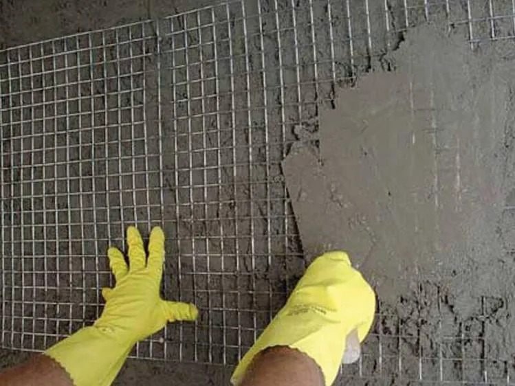 Welded wire mesh being bedded into mortar as plaster and bed-joint reinforcement over blockwork