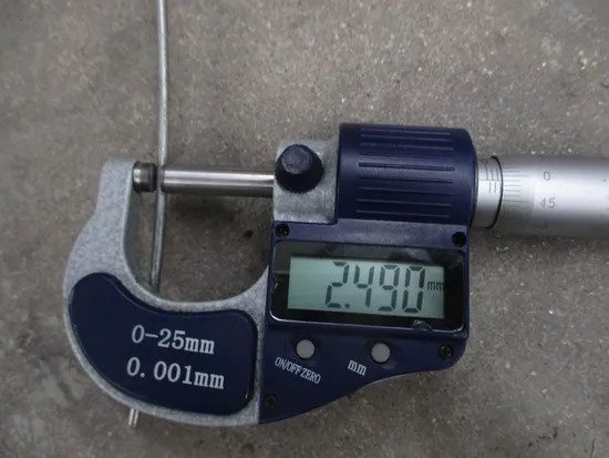 Vernier caliper measuring wire diameter on a weldmesh panel